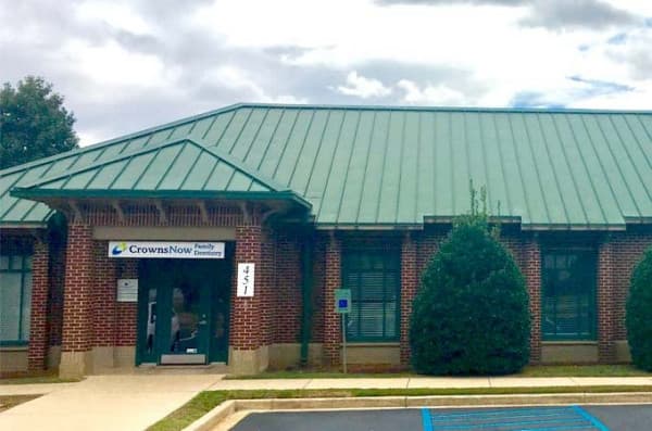 The image shows a building with a green roof and a sign that reads  Crowne News.