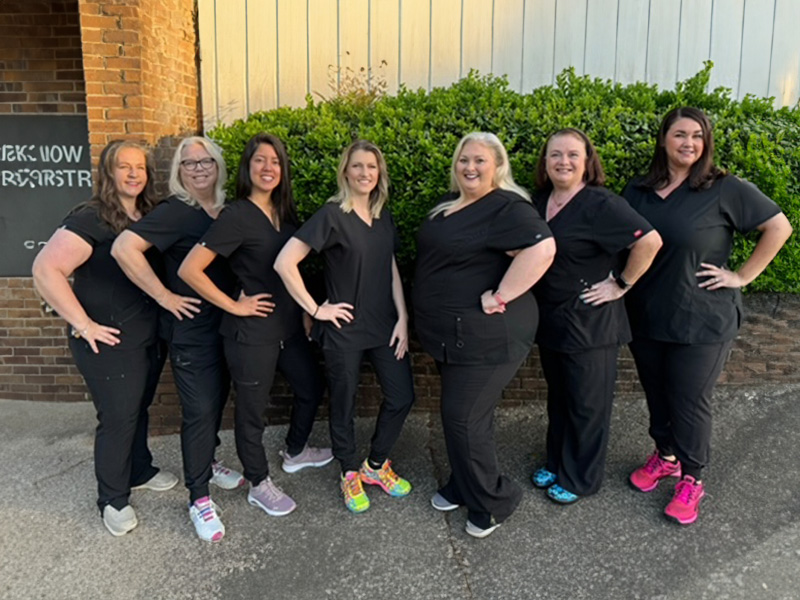 A group of female nurses posing for a photo in front of a building.