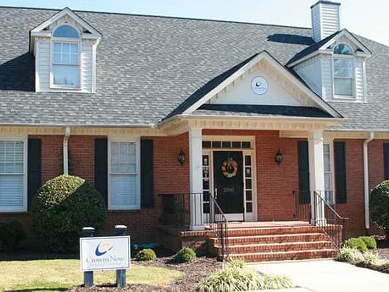 The image shows a two-story residential building with a brick facade, a front porch with columns, and a sign indicating  123 Main Street.