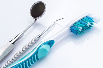 A dental tool set, including a toothbrush and dental instruments, arranged on a white surface.