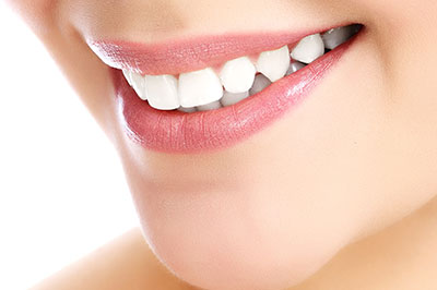 A close-up of a person s face with a focus on their teeth, showcasing a bright smile and dental care product.