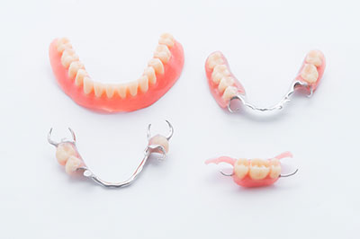 The image displays a set of dentures with missing teeth, presented on a white background.