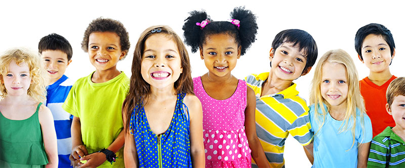 The image shows a diverse group of children and young adults posing for a photo with smiles, wearing various colors of clothing.