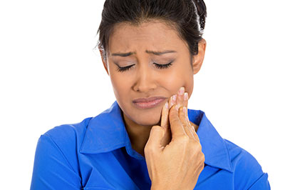 The image shows a woman with her eyes closed, holding her hand to her mouth as if she is in pain or discomfort.