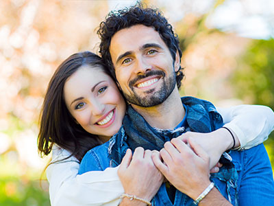 The image depicts a man and woman embracing each other, with the man wearing a blue bandana around his neck.