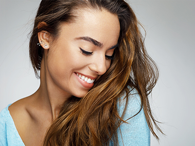 A young woman with long hair and a smile, looking to the side.