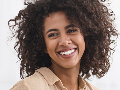 This is a portrait of a woman with curly hair, smiling and looking directly at the camera.